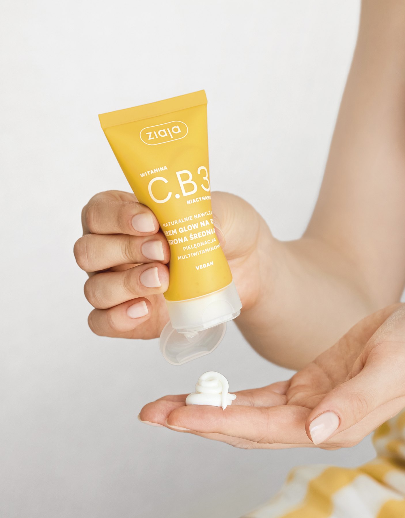 Een hand knijpt dagcrème uit een gele tube Vitamin C.B3 van Ziaja